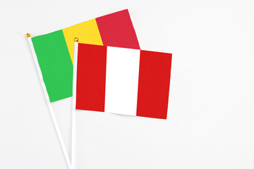 Peru and Mali stick flags on white background. High quality fabric, miniature national flag. Peaceful global concept.White floor for copy space.