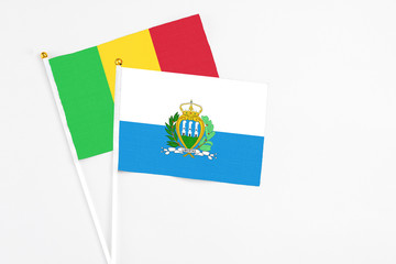 San Marino and Mali stick flags on white background. High quality fabric, miniature national flag. Peaceful global concept.White floor for copy space.