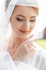 Beautiful bride portrait with veil over her face. Beautiful bride with fashion wedding hairstyle - on white background.Closeup portrait of young gorgeous bride