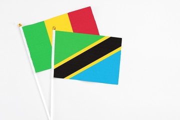 Tanzania and Mali stick flags on white background. High quality fabric, miniature national flag. Peaceful global concept.White floor for copy space.