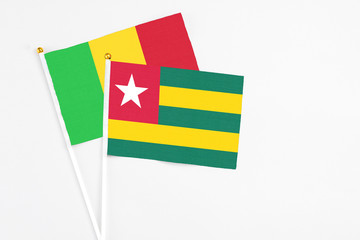 Togo and Mali stick flags on white background. High quality fabric, miniature national flag. Peaceful global concept.White floor for copy space.