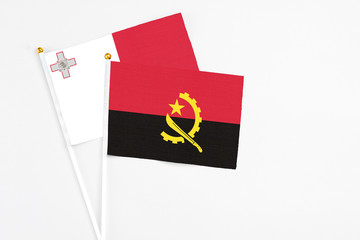 Angola and Malta stick flags on white background. High quality fabric, miniature national flag. Peaceful global concept.White floor for copy space.