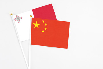 China and Malta stick flags on white background. High quality fabric, miniature national flag. Peaceful global concept.White floor for copy space.