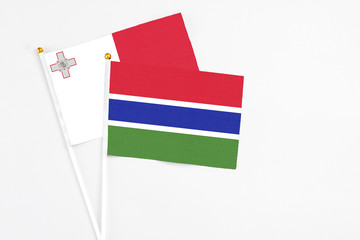 Gambia and Malta stick flags on white background. High quality fabric, miniature national flag. Peaceful global concept.White floor for copy space.