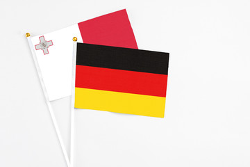 Germany and Malta stick flags on white background. High quality fabric, miniature national flag. Peaceful global concept.White floor for copy space.