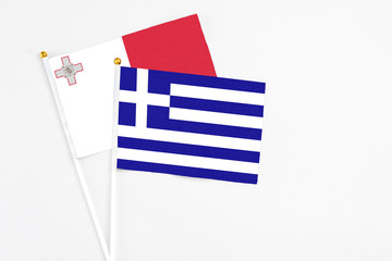 Greece and Malta stick flags on white background. High quality fabric, miniature national flag. Peaceful global concept.White floor for copy space.