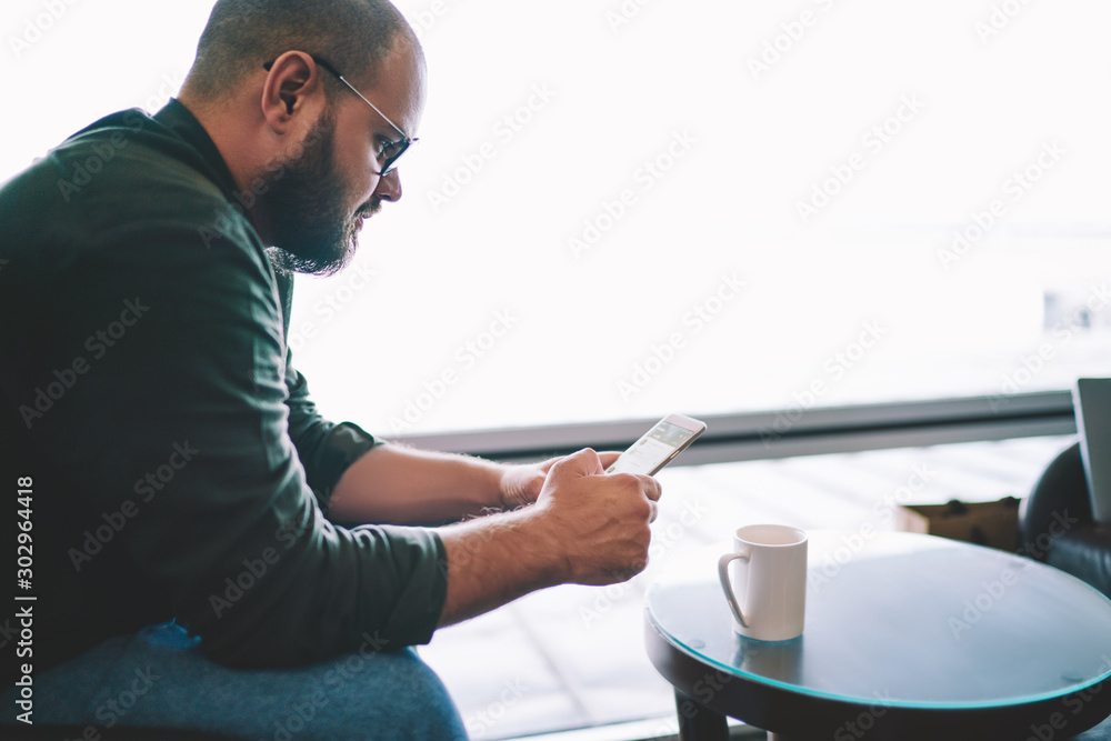 Poster stylish bearded man searching app for installing on smartphone.male blogger in spectacles updating p