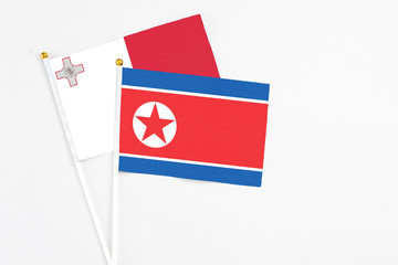 North Korea and Malta stick flags on white background. High quality fabric, miniature national flag. Peaceful global concept.White floor for copy space.