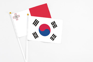 South Korea and Malta stick flags on white background. High quality fabric, miniature national flag. Peaceful global concept.White floor for copy space.