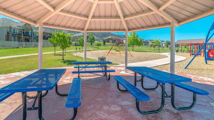Panorama frame Blue picnic table and seats inside an octagon shape pavilion at a sunny park