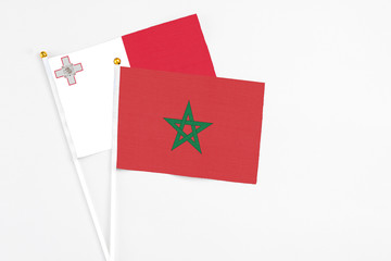 Morocco and Malta stick flags on white background. High quality fabric, miniature national flag. Peaceful global concept.White floor for copy space.