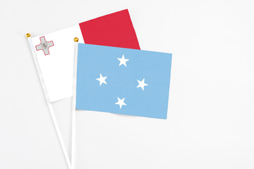 Micronesia and Malta stick flags on white background. High quality fabric, miniature national flag. Peaceful global concept.White floor for copy space.