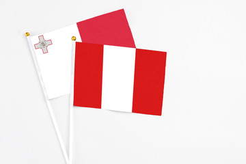 Peru and Malta stick flags on white background. High quality fabric, miniature national flag. Peaceful global concept.White floor for copy space.