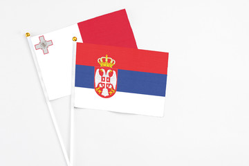 Serbia and Malta stick flags on white background. High quality fabric, miniature national flag. Peaceful global concept.White floor for copy space.