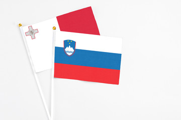 Slovenia and Malta stick flags on white background. High quality fabric, miniature national flag. Peaceful global concept.White floor for copy space.