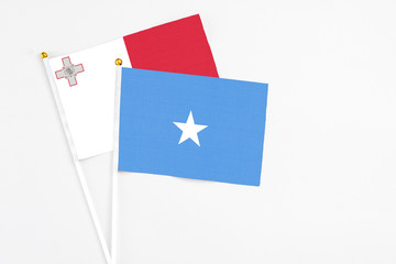 Somalia and Malta stick flags on white background. High quality fabric, miniature national flag. Peaceful global concept.White floor for copy space.