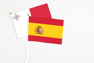 Spain and Malta stick flags on white background. High quality fabric, miniature national flag. Peaceful global concept.White floor for copy space.