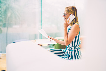 Side view of stylish businesswoman in optical eyeglasses consults with professional on cellular...