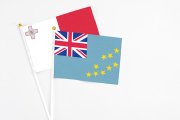 Fototapeta premium Tuvalu and Malta stick flags on white background. High quality fabric, miniature national flag. Peaceful global concept.White floor for copy space.
