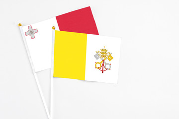 Vatican City and Malta stick flags on white background. High quality fabric, miniature national flag. Peaceful global concept.White floor for copy space.