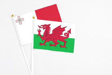 Wales and Malta stick flags on white background. High quality fabric, miniature national flag. Peaceful global concept.White floor for copy space.