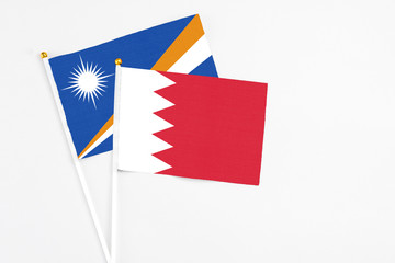 Bahrain and Marshall Islands stick flags on white background. High quality fabric, miniature national flag. Peaceful global concept.White floor for copy space.
