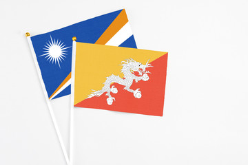 Bhutan and Marshall Islands stick flags on white background. High quality fabric, miniature national flag. Peaceful global concept.White floor for copy space.