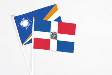 Dominican Republic and Marshall Islands stick flags on white background. High quality fabric, miniature national flag. Peaceful global concept.White floor for copy space.