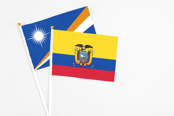 Obraz premium Ecuador and Marshall Islands stick flags on white background. High quality fabric, miniature national flag. Peaceful global concept.White floor for copy space.