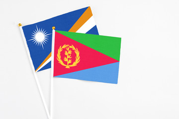 Eritrea and Marshall Islands stick flags on white background. High quality fabric, miniature national flag. Peaceful global concept.White floor for copy space.