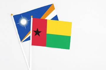 Guinea Bissau and Marshall Islands stick flags on white background. High quality fabric, miniature national flag. Peaceful global concept.White floor for copy space.