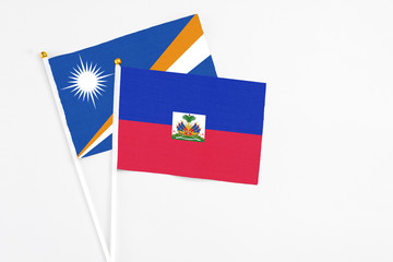 Haiti and Marshall Islands stick flags on white background. High quality fabric, miniature national flag. Peaceful global concept.White floor for copy space.
