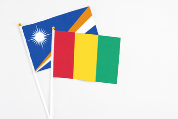 Guinea and Marshall Islands stick flags on white background. High quality fabric, miniature national flag. Peaceful global concept.White floor for copy space.