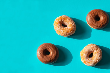Chocolate frosted donuts and sugar coated donuts on bright blue paper background