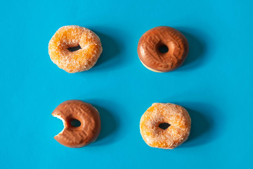 Sugar coated donuts and donuts with chocolate frosting with one donut bitten