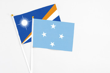Obraz na płótnie Canvas Micronesia and Marshall Islands stick flags on white background. High quality fabric, miniature national flag. Peaceful global concept.White floor for copy space.