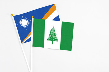 Norfolk Island and Marshall Islands stick flags on white background. High quality fabric, miniature national flag. Peaceful global concept.White floor for copy space.