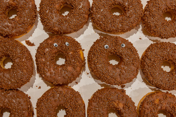 Background of a dozen donuts two of which have googly eyes