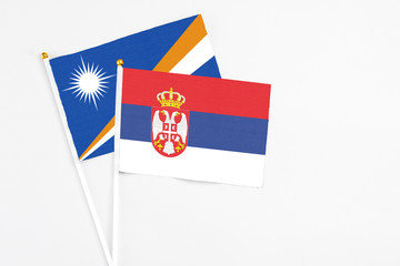 Serbia and Marshall Islands stick flags on white background. High quality fabric, miniature national flag. Peaceful global concept.White floor for copy space.