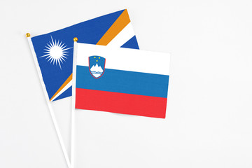 Slovenia and Marshall Islands stick flags on white background. High quality fabric, miniature national flag. Peaceful global concept.White floor for copy space.