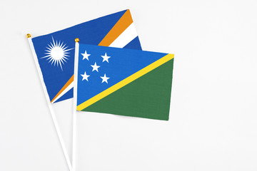 Solomon Islands and Marshall Islands stick flags on white background. High quality fabric,...