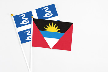 Antigua and Barbuda and Martinique stick flags on white background. High quality fabric, miniature national flag. Peaceful global concept.White floor for copy space.