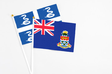 Fototapeta premium Cayman Islands and Martinique stick flags on white background. High quality fabric, miniature national flag. Peaceful global concept.White floor for copy space.