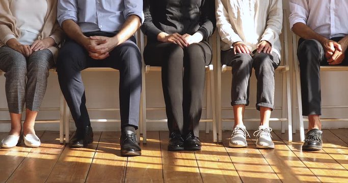 Professional unemployed business people sit on chairs, legs closeup view
