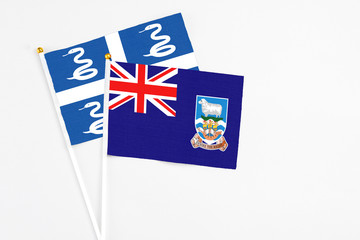 Fototapeta premium Falkland Islands and Martinique stick flags on white background. High quality fabric, miniature national flag. Peaceful global concept.White floor for copy space.