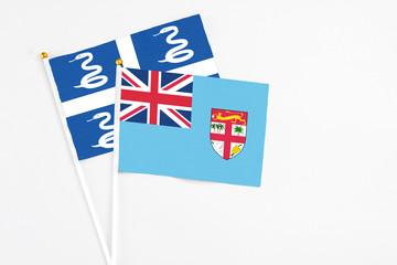 Fototapeta premium Fiji and Martinique stick flags on white background. High quality fabric, miniature national flag. Peaceful global concept.White floor for copy space.