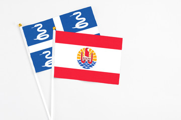 French Polynesia and Martinique stick flags on white background. High quality fabric, miniature national flag. Peaceful global concept.White floor for copy space.