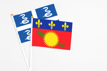 Guadeloupe and Martinique stick flags on white background. High quality fabric, miniature national flag. Peaceful global concept.White floor for copy space.