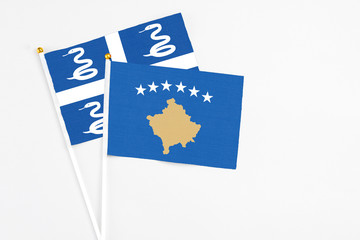 Kosovo and Martinique stick flags on white background. High quality fabric, miniature national flag. Peaceful global concept.White floor for copy space.