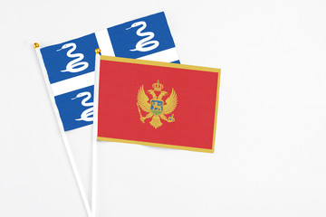 Montenegro and Martinique stick flags on white background. High quality fabric, miniature national flag. Peaceful global concept.White floor for copy space.